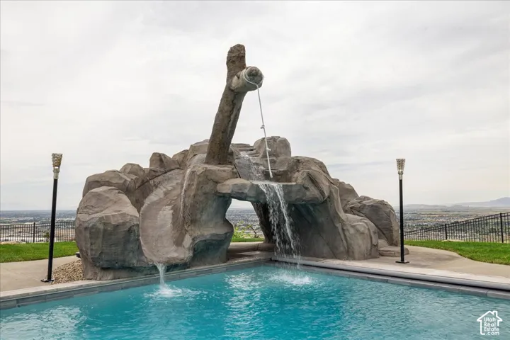 Swimming pool with rock-finish water slide, waterfall feature, and two decorative torch-style light fixtures