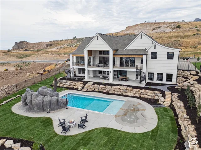 Terraced backyard featuring a swimming pool, integrated spa with fountains, and a rock-feature waterfall