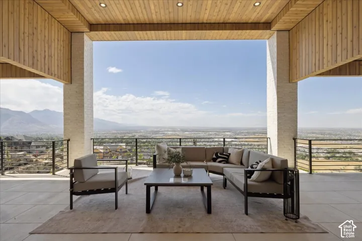 Expansive covered patio featuring a wood-panel ceiling with recessed lighting, tile flooring, and metal railings