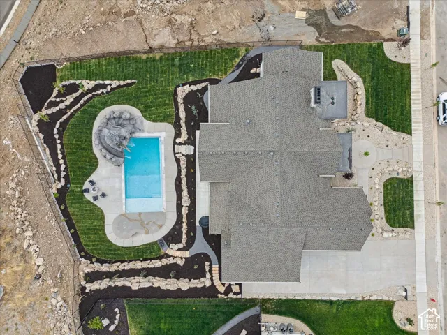 In-ground swimming pool with stone surround, complemented by a rock-lined landscaping and manicured lawn