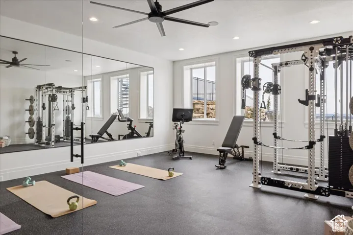 Dedicated fitness room featuring full-wall mirrors, recessed lighting, and a dark ceiling fan