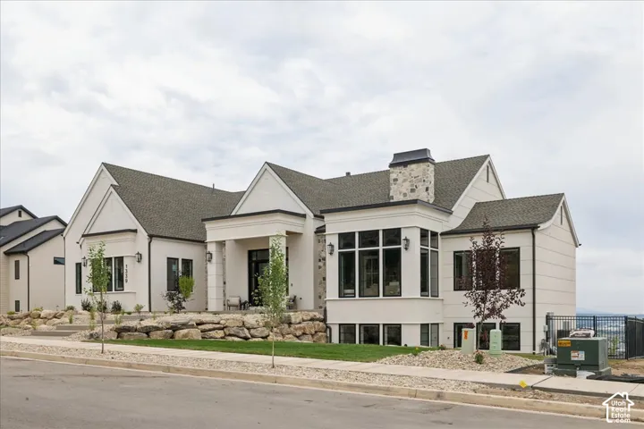 Modern stucco exterior with a stone accent chimney and covered entryway