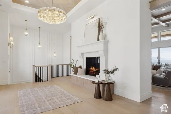 Grand entry with a crystal chandelier, wood-finish flooring, staircase with dark balusters, and a fireplace featuring a mantel and built-in bench