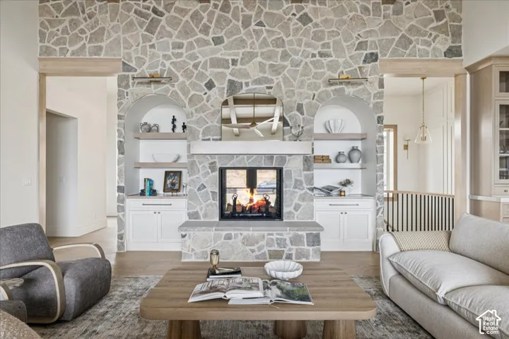 Stone-clad fireplace with mantel and hearth, flanked by arched built-in shelving with lower cabinetry