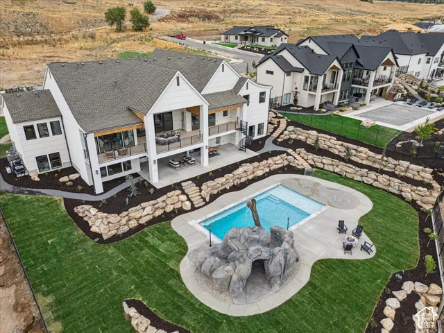 Expansive backyard featuring a swimming pool with a rock grotto, integrated spa, and surrounding concrete decking