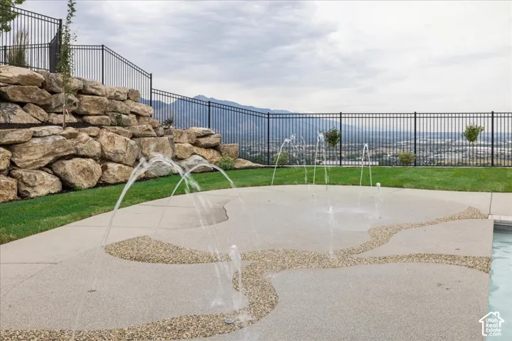 Sleek black metal fencing enclosing a rock retaining wall and green lawn
