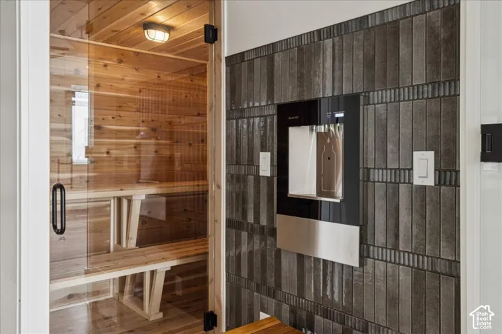Cedar-lined sauna with clear glass door, integrated wooden benches, and wall-mounted light fixture