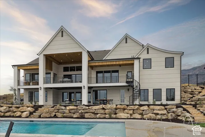 Modern exterior with multiple balconies, a spiral staircase, and a pool