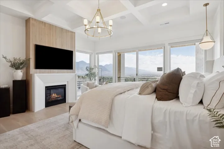Coffered ceiling, wood-finish flooring, built-in fireplace, sliding glass doors, and a decorative chandelier