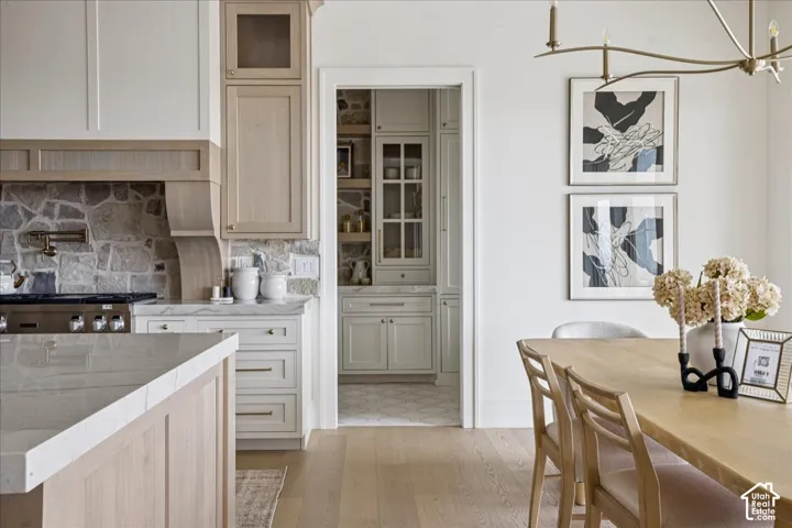 Gourmet kitchen with stone backsplash and custom range hood