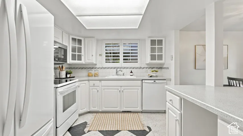 Kitchen featuring white cabinetry, integrated appliances, a single-basin sink, and overhead lighting