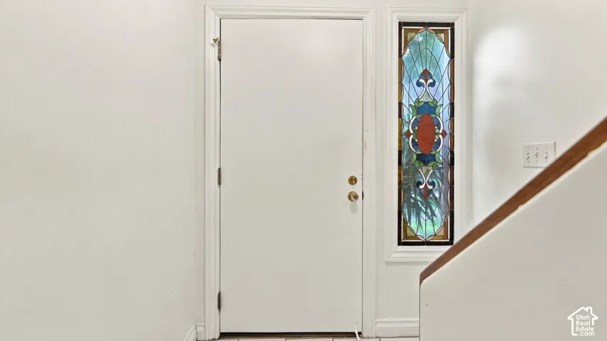 Entryway featuring a white door with brass hardware and an ornate stained glass sidelight