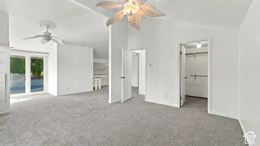 Vaulted ceilings with ceiling fans, sliding glass door, built-in cabinetry, and carpet flooring