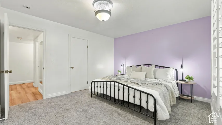 Wall-to-wall carpeting, overhead light fixture, white interior doors, and a lavender accent wall