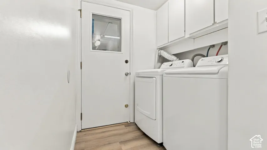 Laundry area featuring wood-finish flooring, white cabinetry, and a white exterior door with a window pane