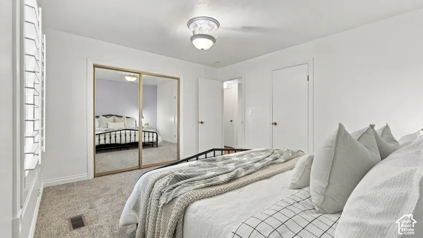 Light-colored carpeted flooring, mirrored closet doors, and white paneled interior doors