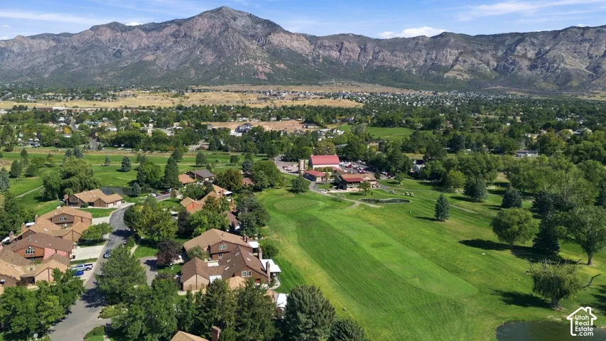 Expansive residential area with a golf course, mature trees, and mountainous terrain