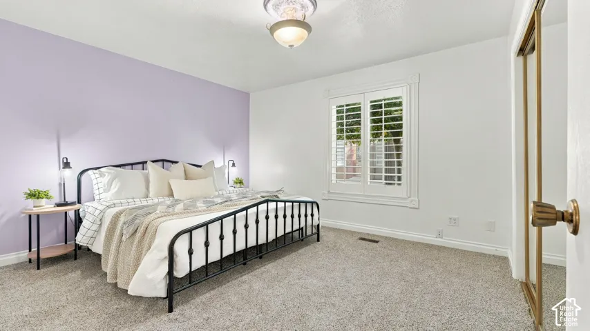 Wall-to-wall carpeting, window with plantation shutters, decorative window casing, ceiling-mounted light fixture, and mirrored closet doors