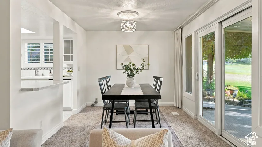 Dining area with a decorative ceiling fixture, sliding glass door, and a partial wall opening to the kitchen