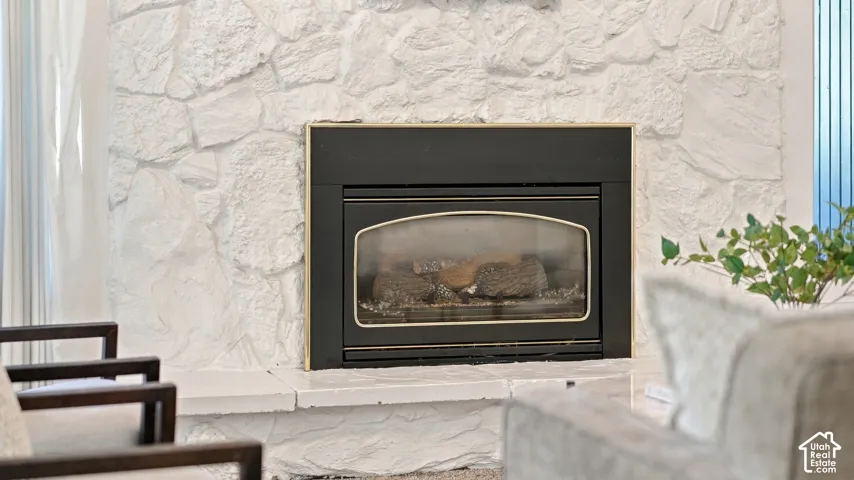 Stone-clad fireplace featuring a black insert and gold-tone trim