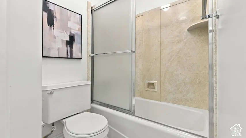 Shower/tub combination with sliding frosted glass doors, integrated curved shelf, and textured wall surround