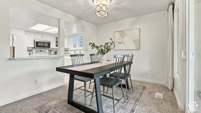 Dining area featuring a contemporary chandelier and light-toned carpeting
