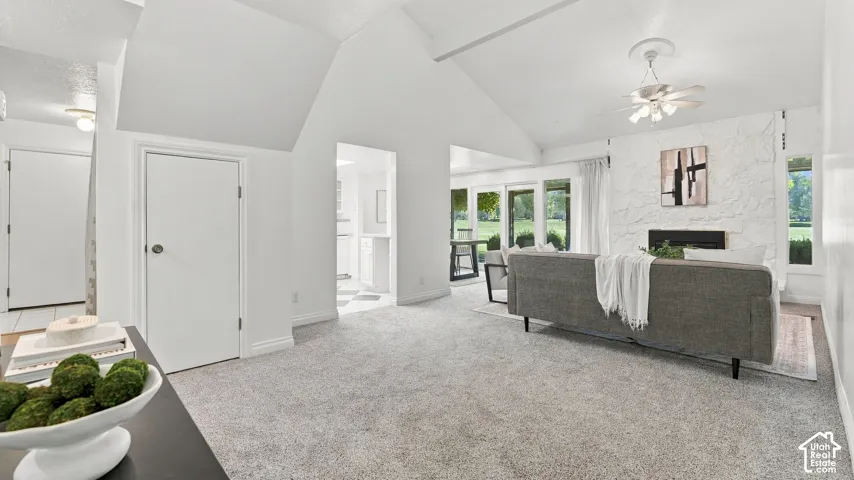 Vaulted ceiling, fireplace with textured surround, ceiling fan, and sliding glass doors to the exterior