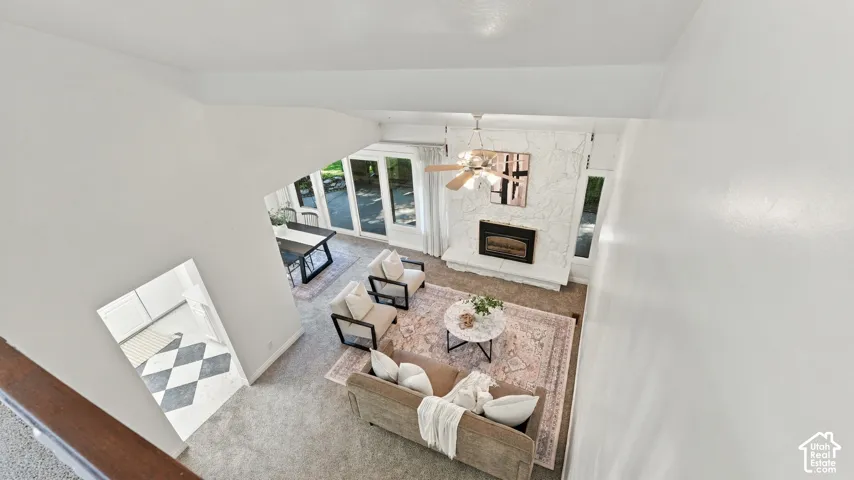 Vaulted ceiling living area featuring a stone-clad fireplace and wood-finish ceiling fan