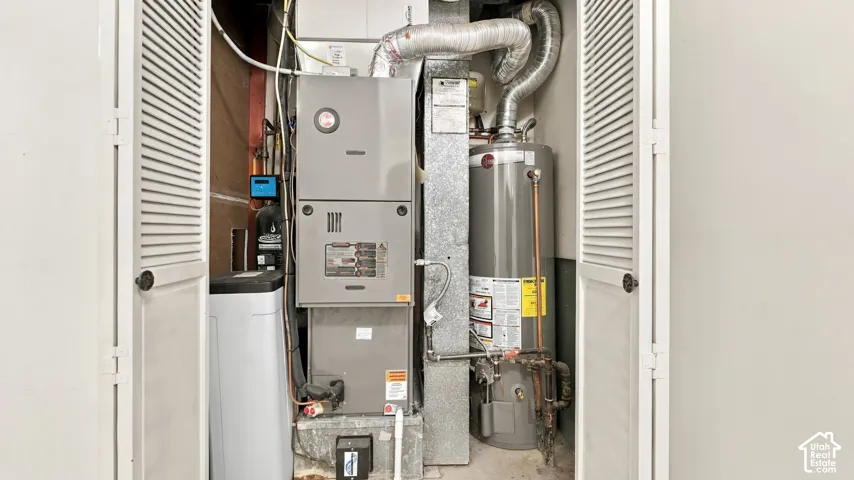Utility closet featuring a water heater, furnace, and water softener