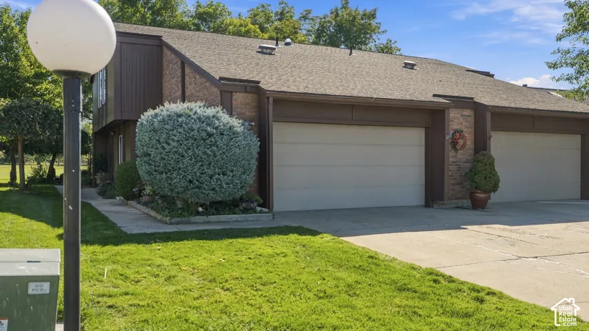 Exterior featuring a pitched shingle roof, brown siding, brick accents, and attached garages