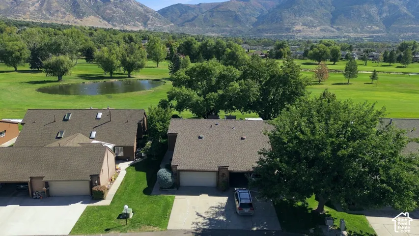 Expansive green space with mature trees, mountain backdrop, and a visible water feature