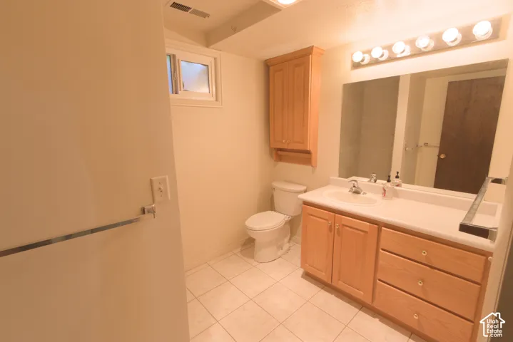 Bathroom featuring a wood-finish vanity with an integrated sink, a built-in wood-finish wall cabinet, a rectangular mirror, and tile flooring
