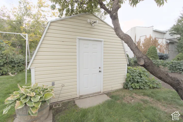 Exterior storage shed with horizontal siding, white door, and security lighting