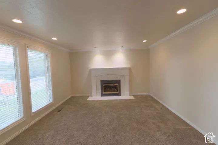 Recessed lighting, crown molding, white trim, carpet flooring, fireplace with stone surround