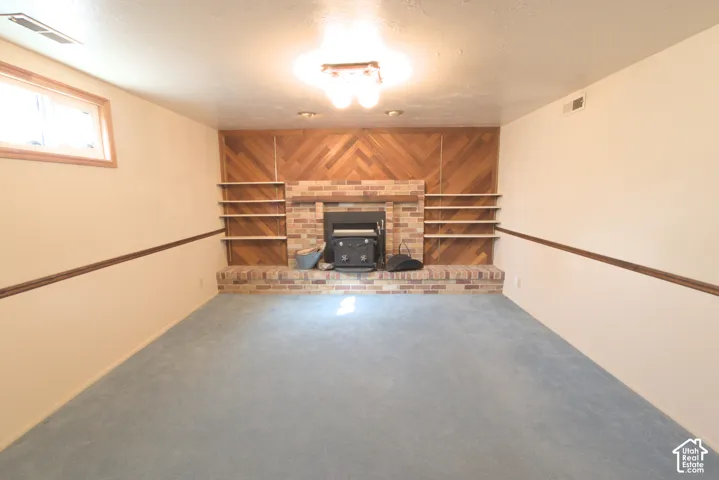 Built-in brick fireplace with hearth, wood-paneled accent wall, integrated shelving, and wall-mounted lighting