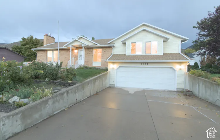 residence featuring a two-car garage, concrete driveway, brick and siding exterior, and a covered front entry
