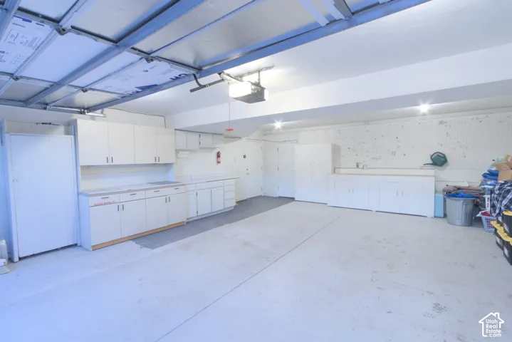 Attached garage with concrete flooring, built-in cabinetry, overhead lighting, and an overhead garage door mechanism