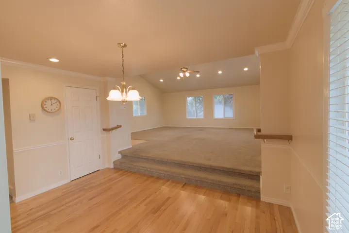 Hardwood flooring, two-tier room design, recessed lighting, vaulted ceiling, and an integrated ceiling fan