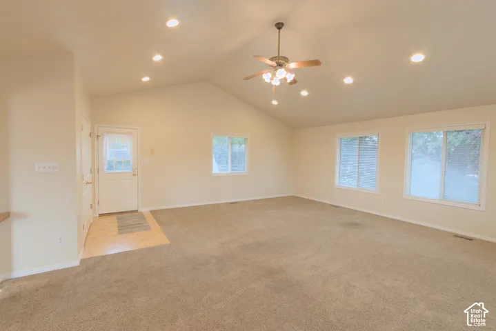 Vaulted ceiling with recessed lighting and a ceiling fan, light-colored carpeting, and a wood-finish flooring entryway
