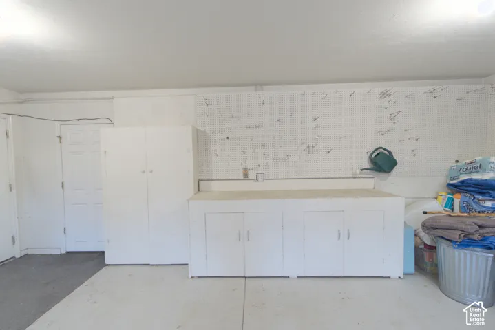 Built-in cabinetry with counter space, additional storage cabinet, and pegboard wall
