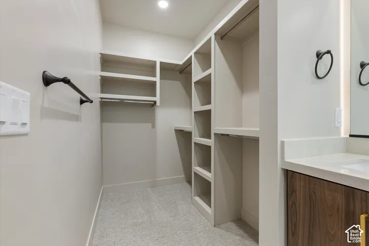 Built-in closet organization system, recessed lighting, carpeted flooring, integrated vanity with a quartz countertop, and a wood-finish cabinet