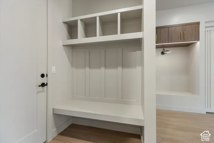 Built-in bench seating with cubby storage, wood-finish flooring, and a dedicated alcove with accent lighting and wood-look cabinetry