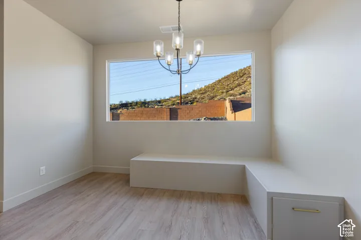 Window with natural scenery, built-in bench seating, integrated storage drawer, wood-finish flooring, and a contemporary multi-light chandelier