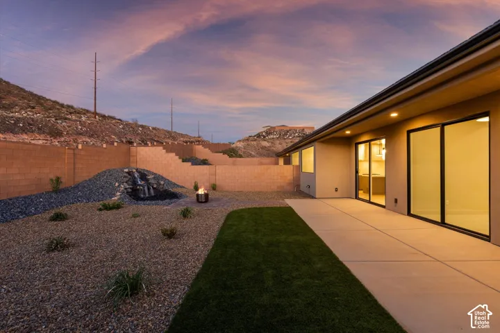 Expansive rear patio with concrete paving, turf sections, and decorative rock landscaping