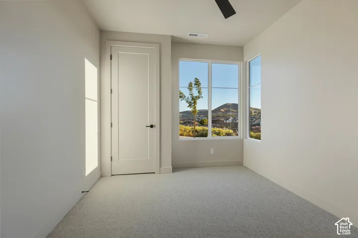 Recessed lighting, large windows, mountain scenery, light-colored carpeting, and a modern interior door