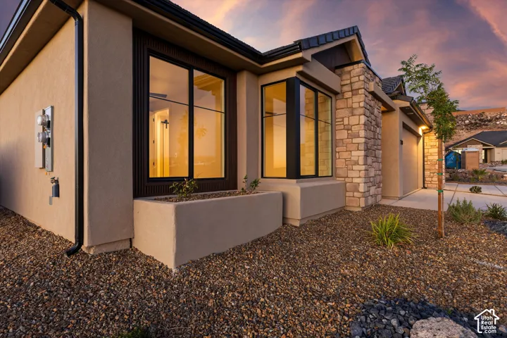 Stucco exterior featuring stacked stone accents, a tiled roof, and a built-in planter box
