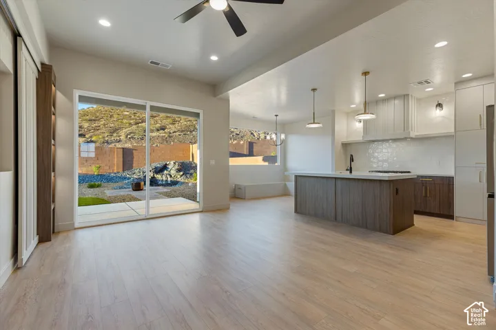 Open-concept living area featuring light wood-finish flooring, recessed lighting, and a ceiling fan