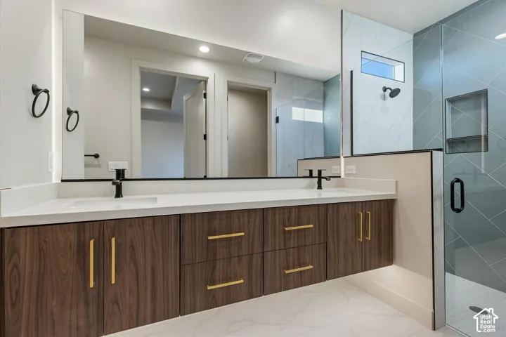 Dual vanity with wood-finish cabinetry, gold-tone hardware, and integrated sinks
