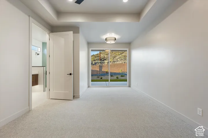 Recessed lighting, tray ceiling, sliding glass door, mountain scenery, and carpet flooring