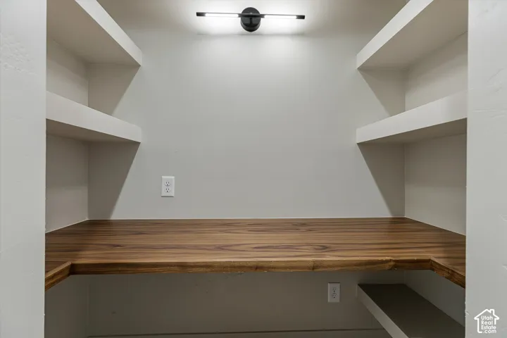Built-in wood-finish desktop with integrated shelving, overhead lighting, and wall outlets
